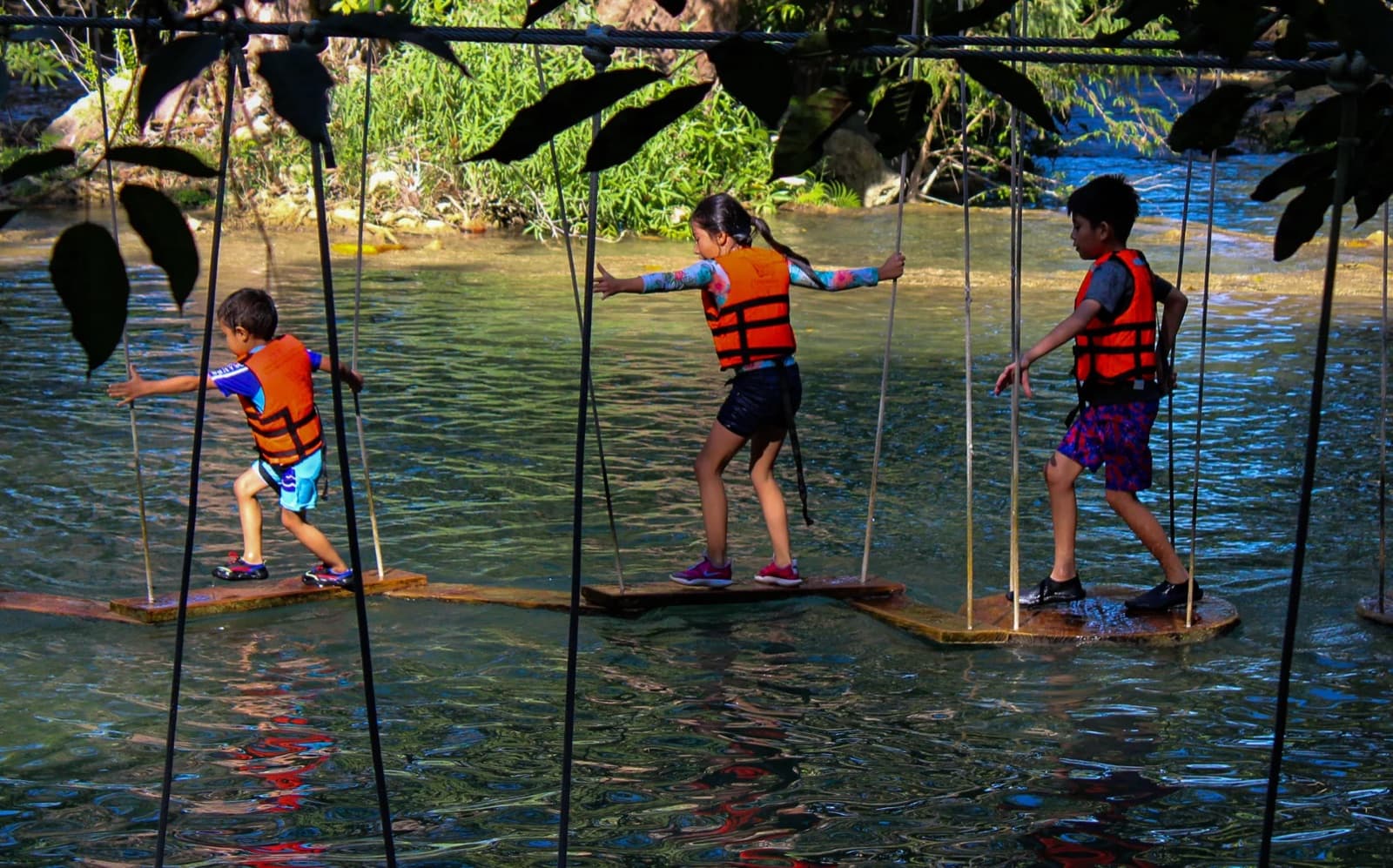 Niños cruzando un puente de cuerdas con chaleco salvavidas en un tour de la Huasteca Potosina